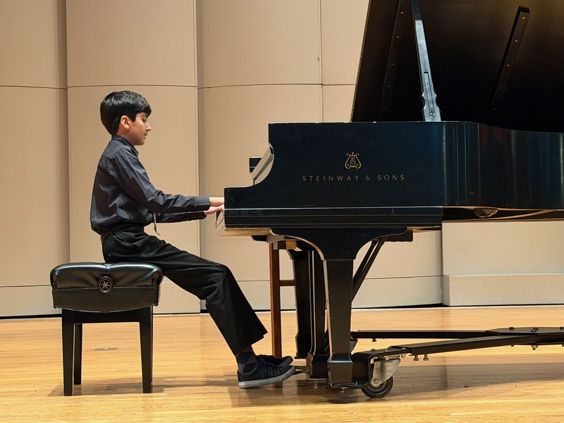 A Caruth Piano Studio student performing at a Steinway grand piano on a concert stage